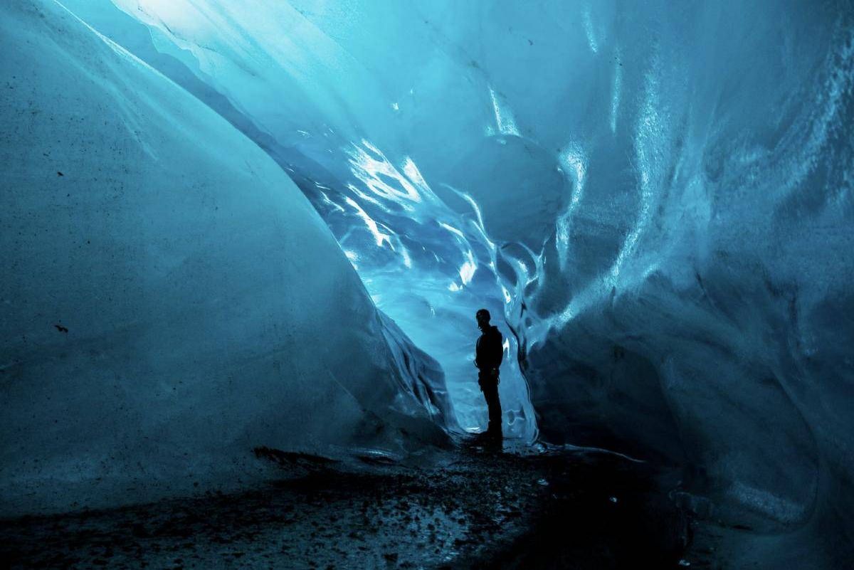 A person standing inside a blue glacier ice cave in Iceland